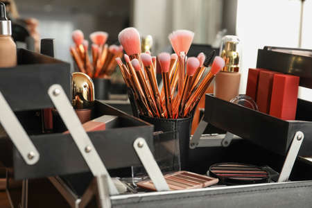 Box with set of brushes and decorative cosmetics on table of makeup artistの写真素材