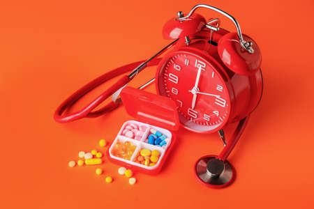 Clock, stethoscope and pills on color backgroundの写真素材