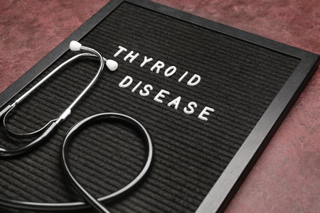 Board with text THYROID DISEASE and stethoscope on color backgroundの写真素材