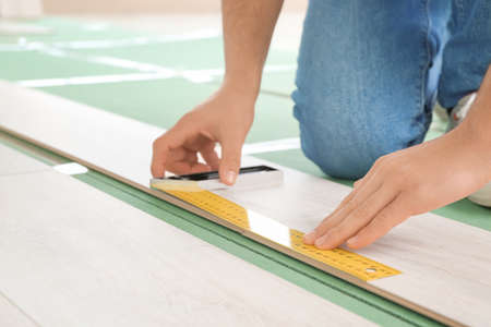 Carpenter installing laminate flooring in roomの写真素材