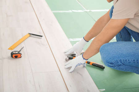 Carpenter installing laminate flooring in roomの写真素材