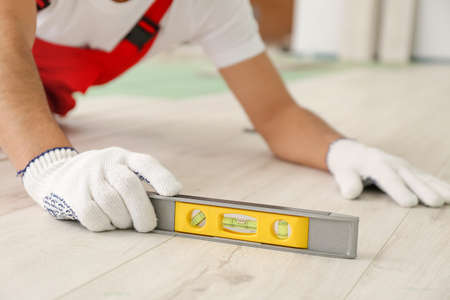 Carpenter installing laminate flooring in roomの写真素材