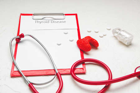 Clipboard with text THYROID DISEASE, pills and stethoscope on white backgroundの写真素材