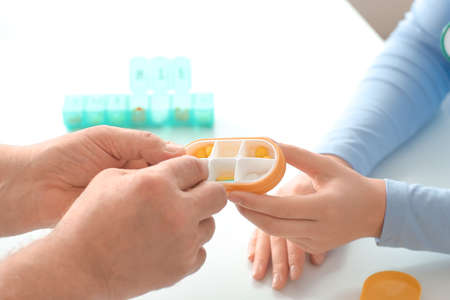 Doctor giving pills to patient in clinic, closeup