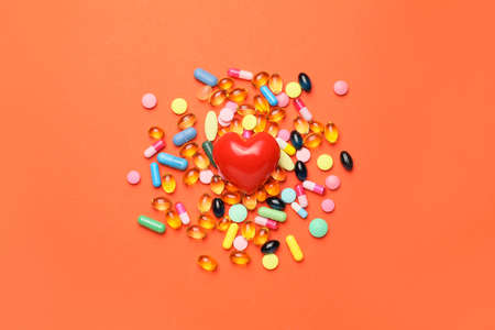 Red heart and pills on color background. Cardiology conceptの写真素材