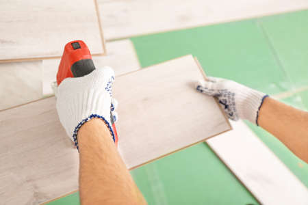 Carpenter installing laminate flooring in roomの写真素材