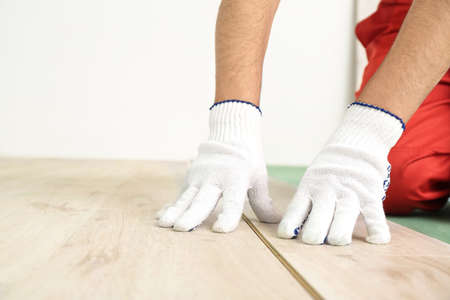 Carpenter installing laminate flooring in roomの写真素材