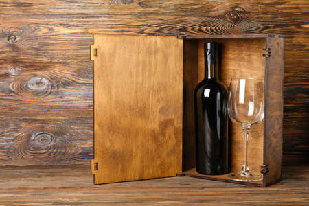 Box with bottle of wine and glass on wooden backgroundの写真素材
