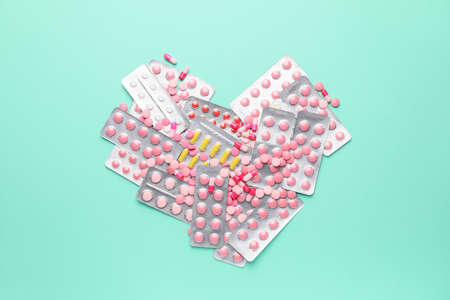 Heart made of blisters with pills on color backgroundの写真素材