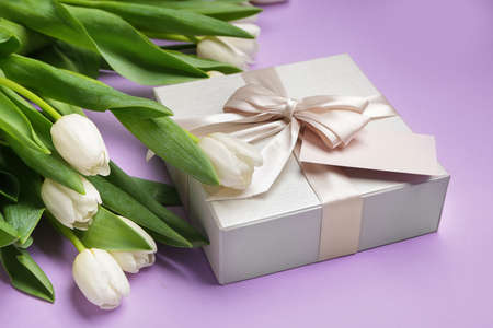 Gift and beautiful flowers on color backgroundの写真素材