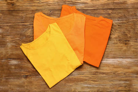 Different stylish t-shirts on wooden background