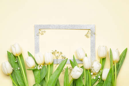 Blank frame and beautiful flowers on color background