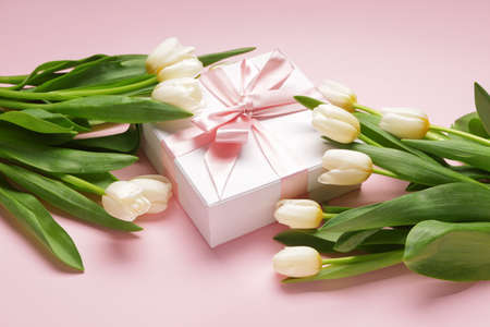Gift and beautiful flowers on color backgroundの写真素材