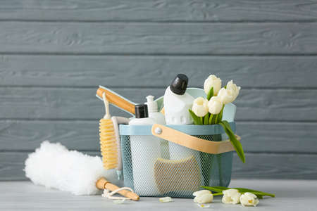 Set of cleaning supplies and spring flowers on gray wooden background