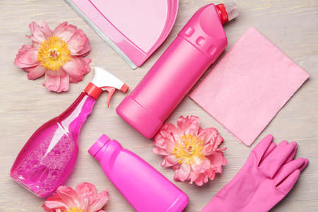 Set of cleaning supplies and spring flowers on wooden background