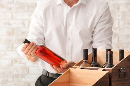 Man with bottles of wine in box on brick backgroundの写真素材