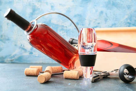 Wine aerator with bottles on color background