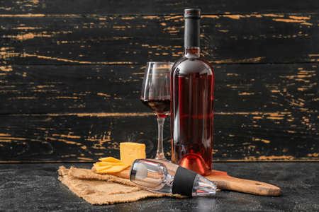 Aerator with glass, bottle of wine and cheese on dark backgroundの写真素材
