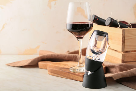 Aerator with glass and bottles of wine on tableの写真素材