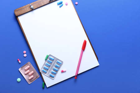 Clipboard with pen and pills on color background. Concept of anorexiaの写真素材