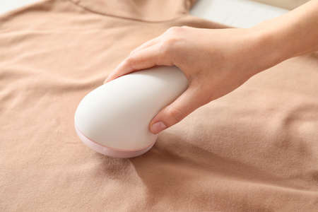 Woman using fabric shaver at homeの写真素材