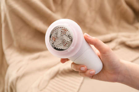 Woman with fabric shaver at homeの写真素材