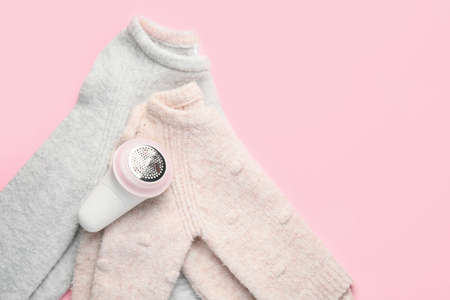 Modern fabric shaver and clothes on color backgroundの写真素材