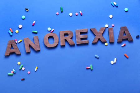 Word ANOREXIA with pills on color backgroundの写真素材