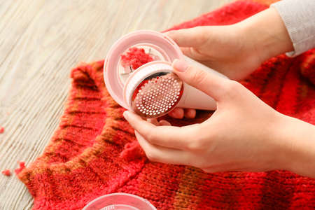 Woman cleaning fabric shaver at homeの写真素材