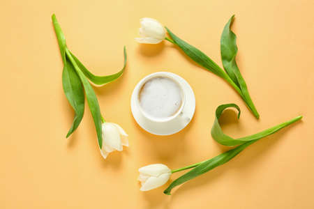 Cup of coffee and flowers on color backgroundの写真素材