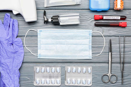 Medical mask, remedy, rubber gloves and infrared thermometer on wooden backgroundの写真素材