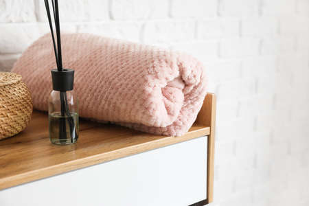 Plaid with aroma freshener on chest of drawers in roomの写真素材