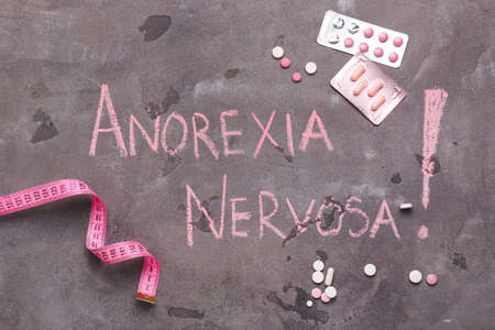 Measuring tape and pills with text ANOREXIA NERVOSA on grunge backgroundの写真素材
