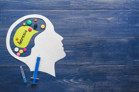 Paper figure of human head with pills and word ANOREXIA on wooden backgroundの写真素材