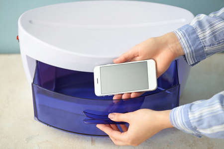 Woman putting mobile phone into ultraviolet sterilizer, closeupの写真素材