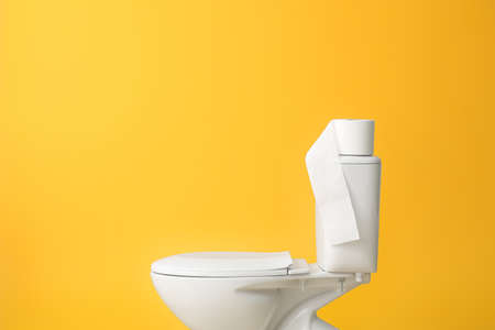 Toilet bowl with roll of paper on color backgroundの写真素材