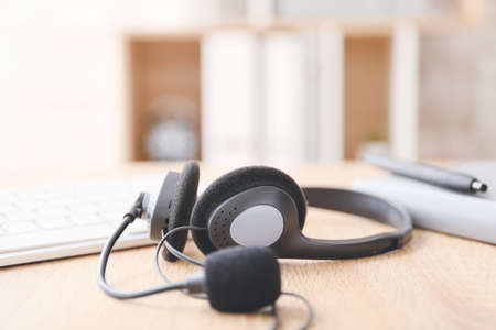 Headset, notebook and PC keyboard on table of technical support agent in officeの写真素材