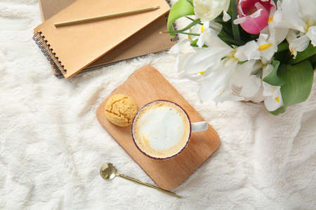 Cup of coffee, flowers, cookie and notebook on soft plaidの写真素材