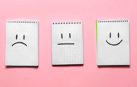 Notebooks with drawn sad, happy and neutral faces on color backgroundの写真素材