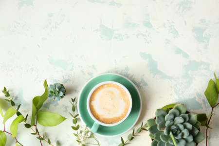 Cup of coffee and green plants on color backgroundの写真素材