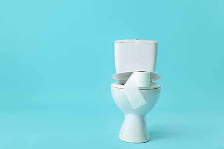 Toilet bowl with roll of paper on color backgroundの写真素材