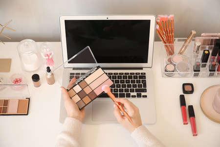 Makeup artist at table with modern laptop and cosmeticsの写真素材