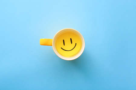 Cup with paper smile on color backgroundの写真素材