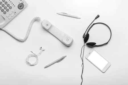 Headset, pens, earphones and telephone with mobile phone on white backgroundの写真素材