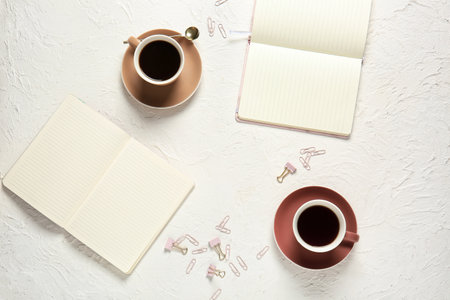 Cups of coffee and notebooks on light backgroundの写真素材