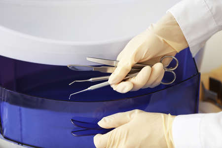 Doctor putting medical instruments into ultraviolet sterilizer in clinic, closeupの写真素材