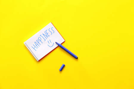 Notebook with word HAPPINESS and marker on color backgroundの写真素材