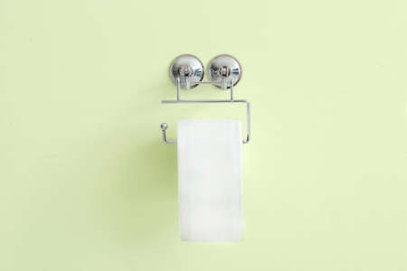 Holder with roll of toilet paper hanging on wallの写真素材