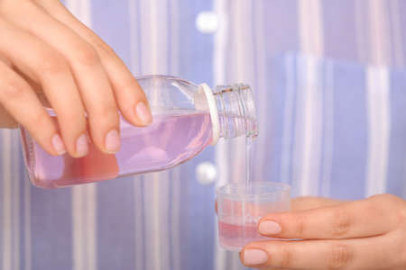 Woman pouring cough syrup from bottle into cup, closeupの写真素材