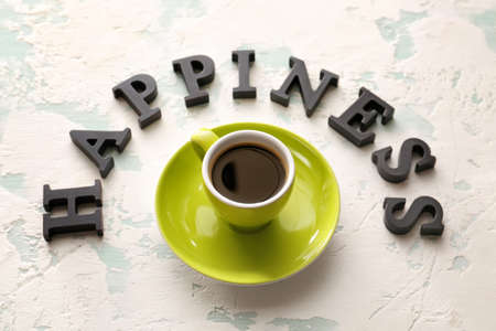 Cup of coffee with word HAPPINESS on light backgroundの写真素材